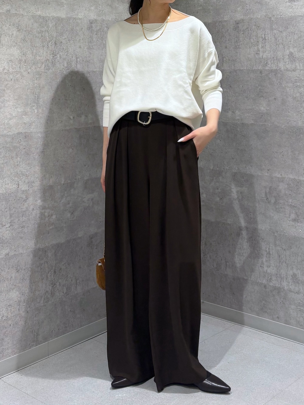 ホワイト系のニット/セーター、ブラウン系のスラックス、ブラウン系のパンプスを着用したレディースの冬コーディネートの3枚目の写真