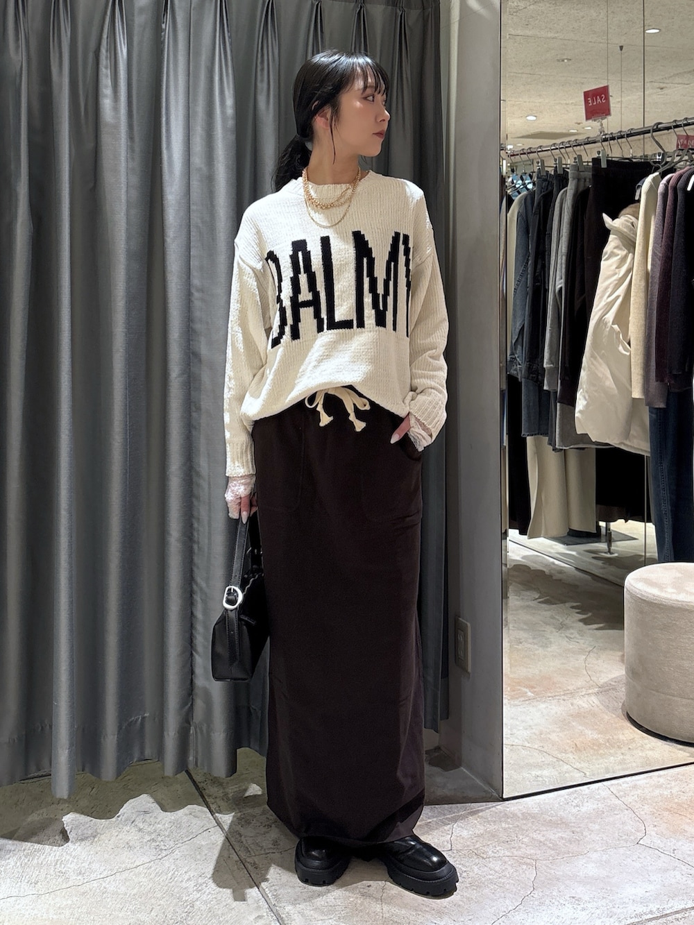 ホワイト系のニット/セーター、ブラウン系のスカート、ブラック系のブーツを着用したレディースの冬コーディネートの2枚目の写真