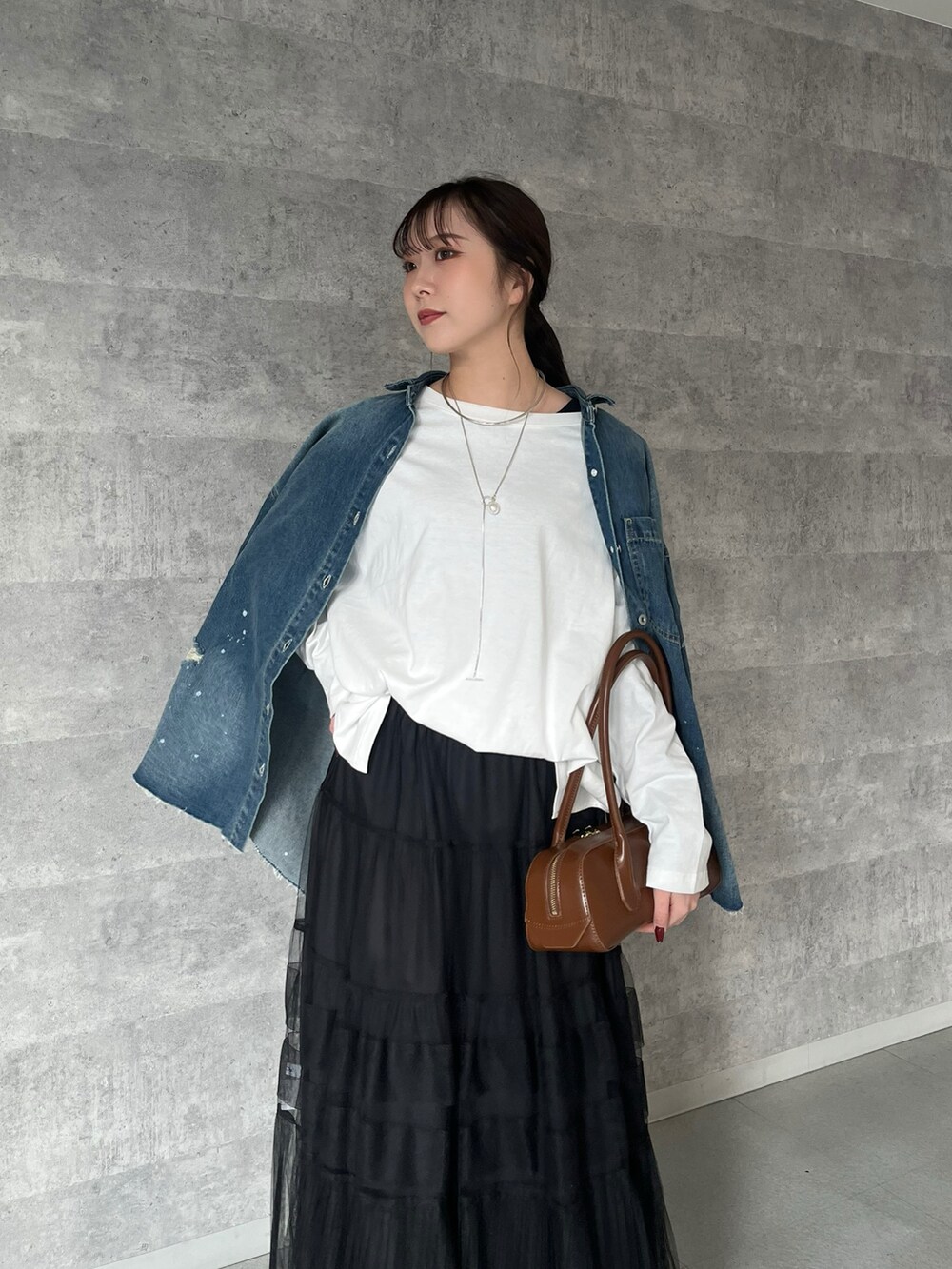 ブラック系のスカート、ブラウン系のショルダーバッグ、ホワイト系のTシャツ/カットソーを着用したレディースの冬コーディネートの2枚目の写真