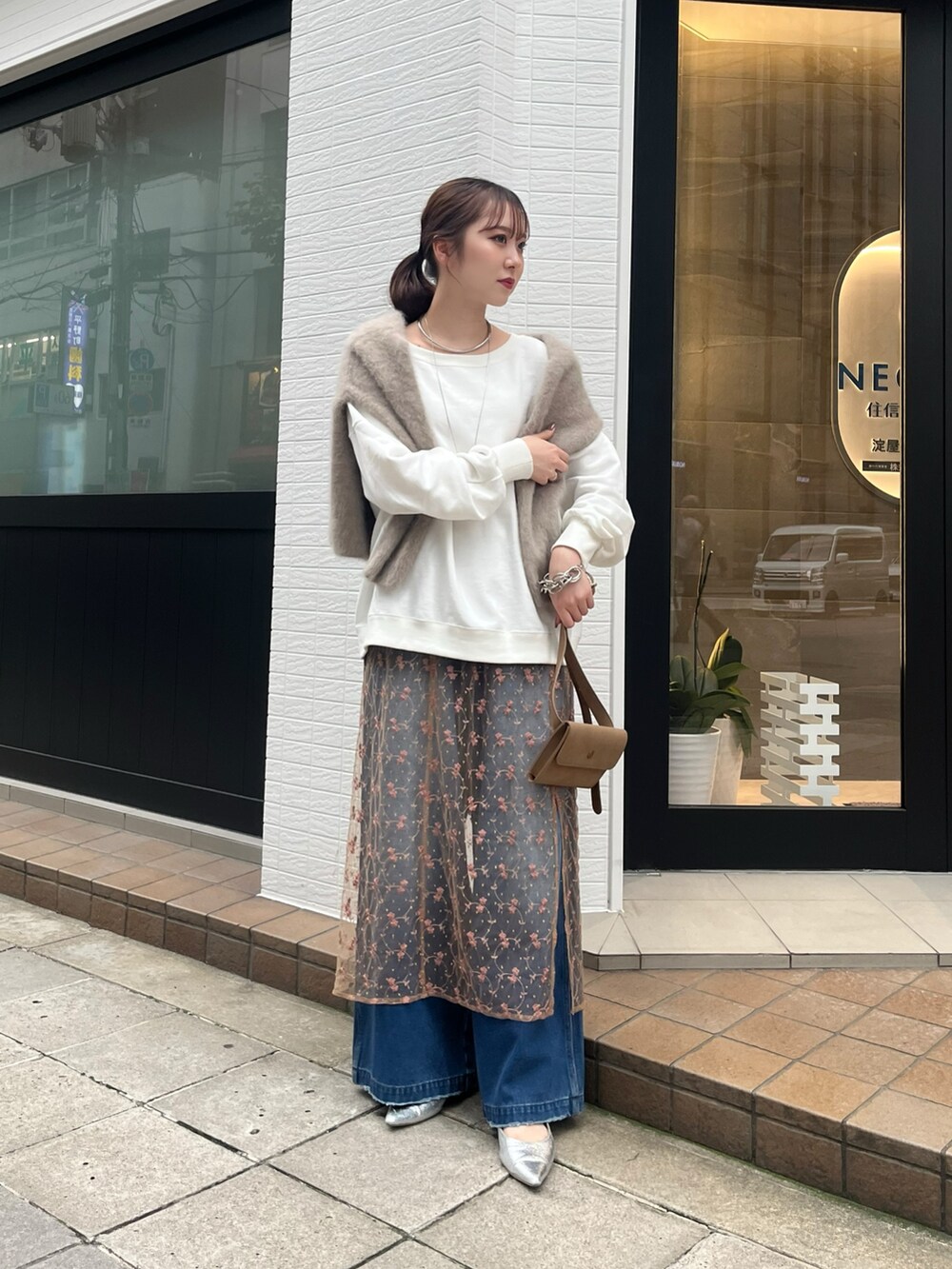 ピンク系のスカート、ブルー系のデニムパンツ、ベージュ系のショルダーバッグを着用したレディースの秋コーディネートの4枚目の写真