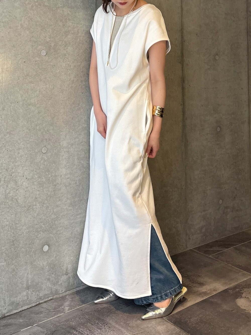 ホワイト系のワンピース、ブルー系のデニムパンツ、ベージュ系のニット/セーターを着用したレディースの春コーディネートの2枚目の写真