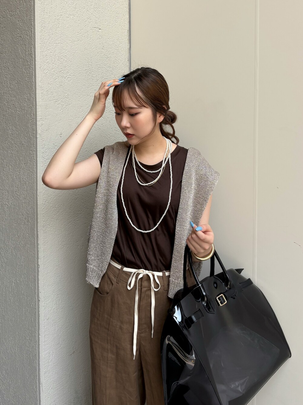 ブラック系のサンダル、ブラック系のショルダーバッグ、ゴールド系のニット/セーターを着用したレディースの夏コーディネートの2枚目の写真