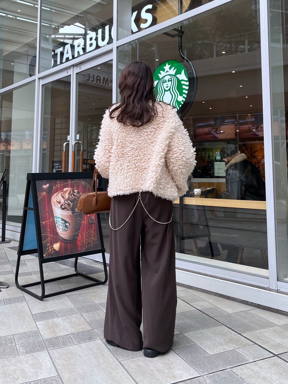 ブラウン系のスラックス、ブラウン系のショルダーバッグ、ベージュ系のカーディガン/ボレロを着用したレディースの冬コーディネートの2枚目の写真