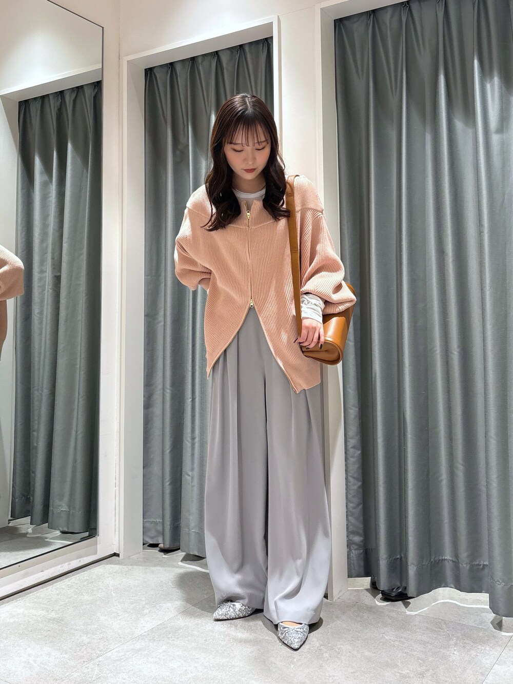 ベージュ系のスラックス、ピンク系のニット/セーター、ブラウン系のショルダーバッグを着用したレディースの冬コーディネートの4枚目の写真