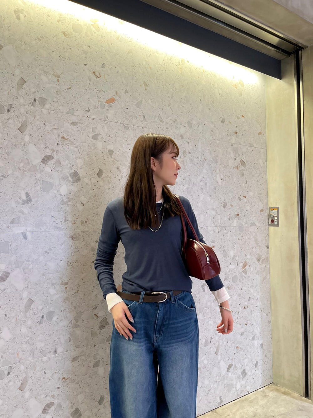 ブルー系のデニムパンツ、シルバー系のパンプス、ホワイト系のTシャツ/カットソーを着用したレディースの秋コーディネートの4枚目の写真