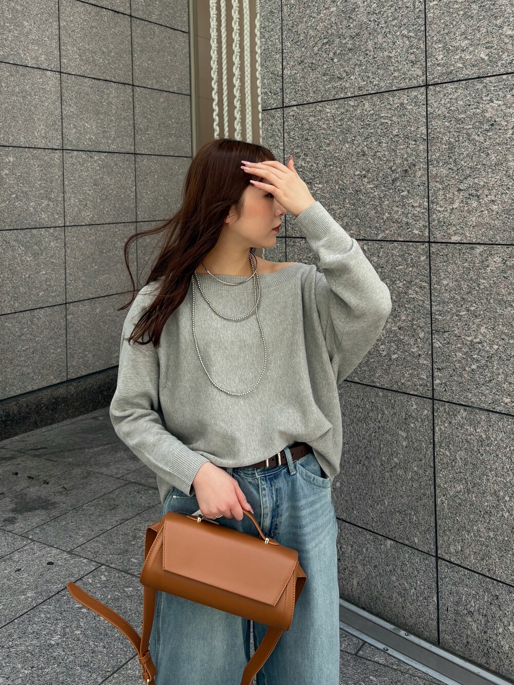 ブルー系のデニムパンツ、グレー系のニット/セーター、ブラウン系のショルダーバッグを着用したレディースの春コーディネートの4枚目の写真