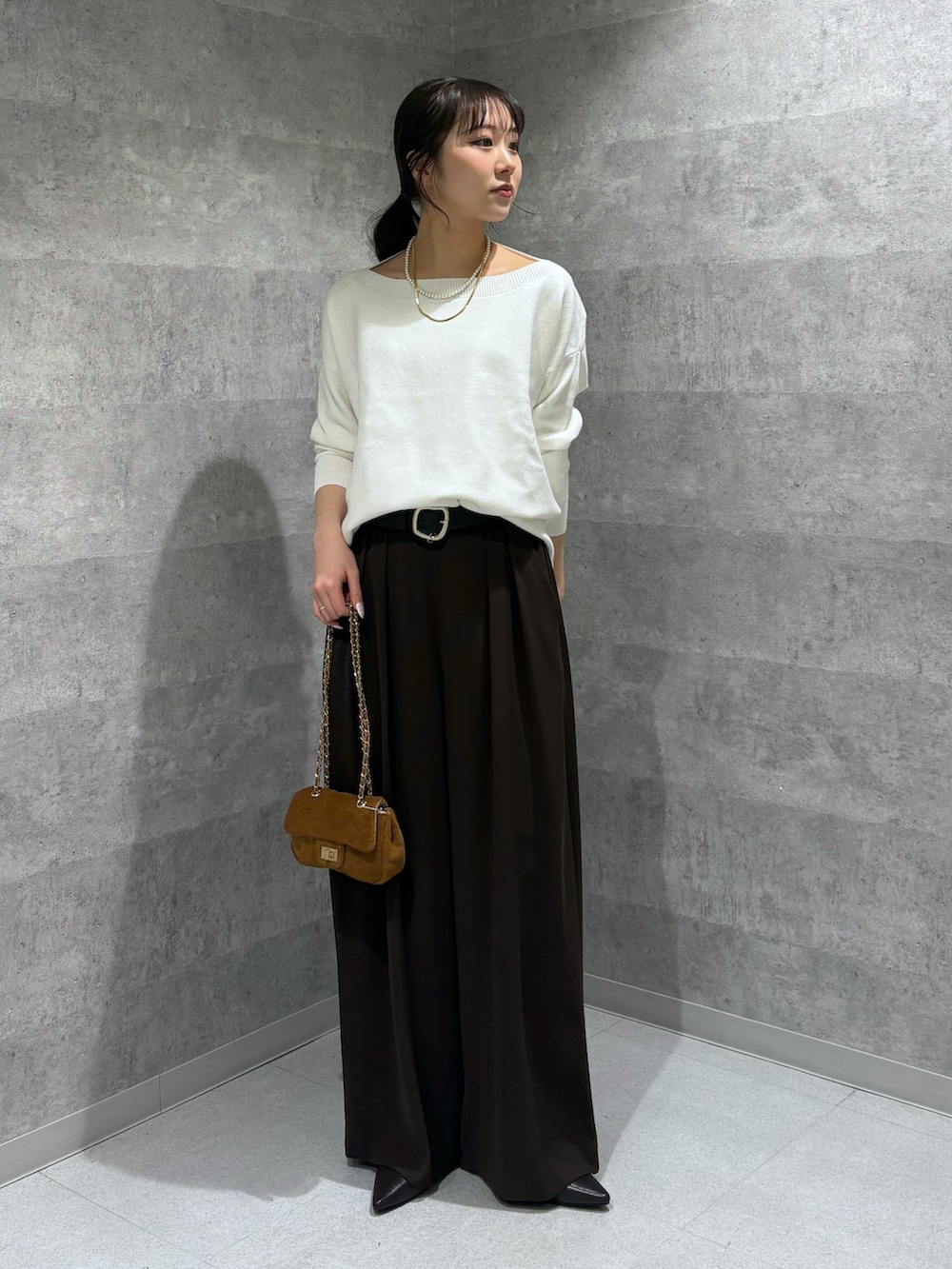 ホワイト系のニット/セーター、ブラウン系のスラックス、ブラウン系のパンプスを着用したレディースの冬コーディネートの2枚目の写真