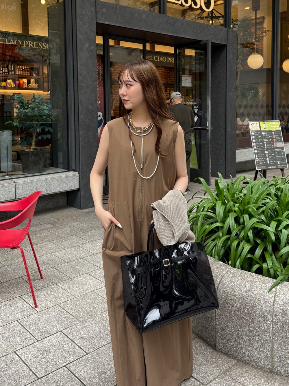 ベージュ系のつなぎ/オールインワン、ブラック系のショルダーバッグ、ゴールド系のニット/セーターを着用したレディースの夏コーディネートの2枚目の写真