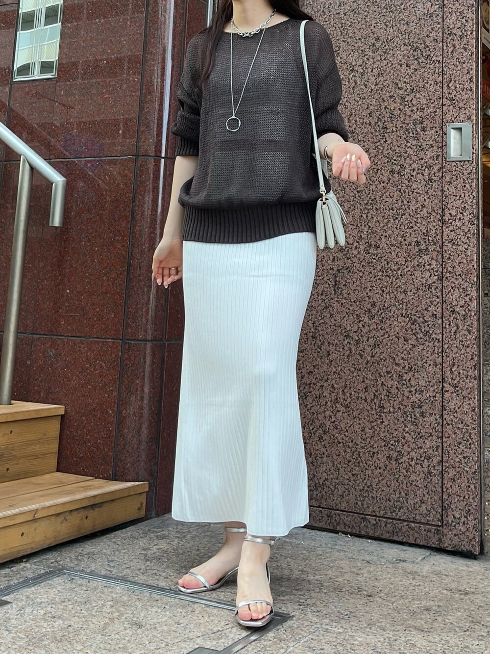 ブラウン系のニット/セーター、ホワイト系のスカート、シルバー系のサンダルを着用したレディースの夏コーディネートの4枚目の写真