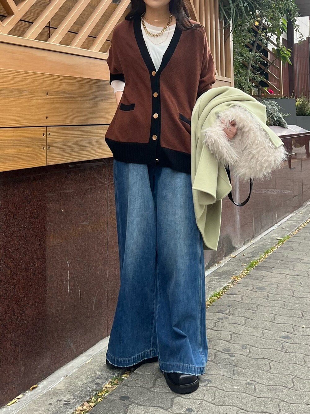 ブルー系のデニムパンツ、グリーン系のその他アウター、ホワイト系のショルダーバッグを着用したレディースの冬コーディネートの4枚目の写真