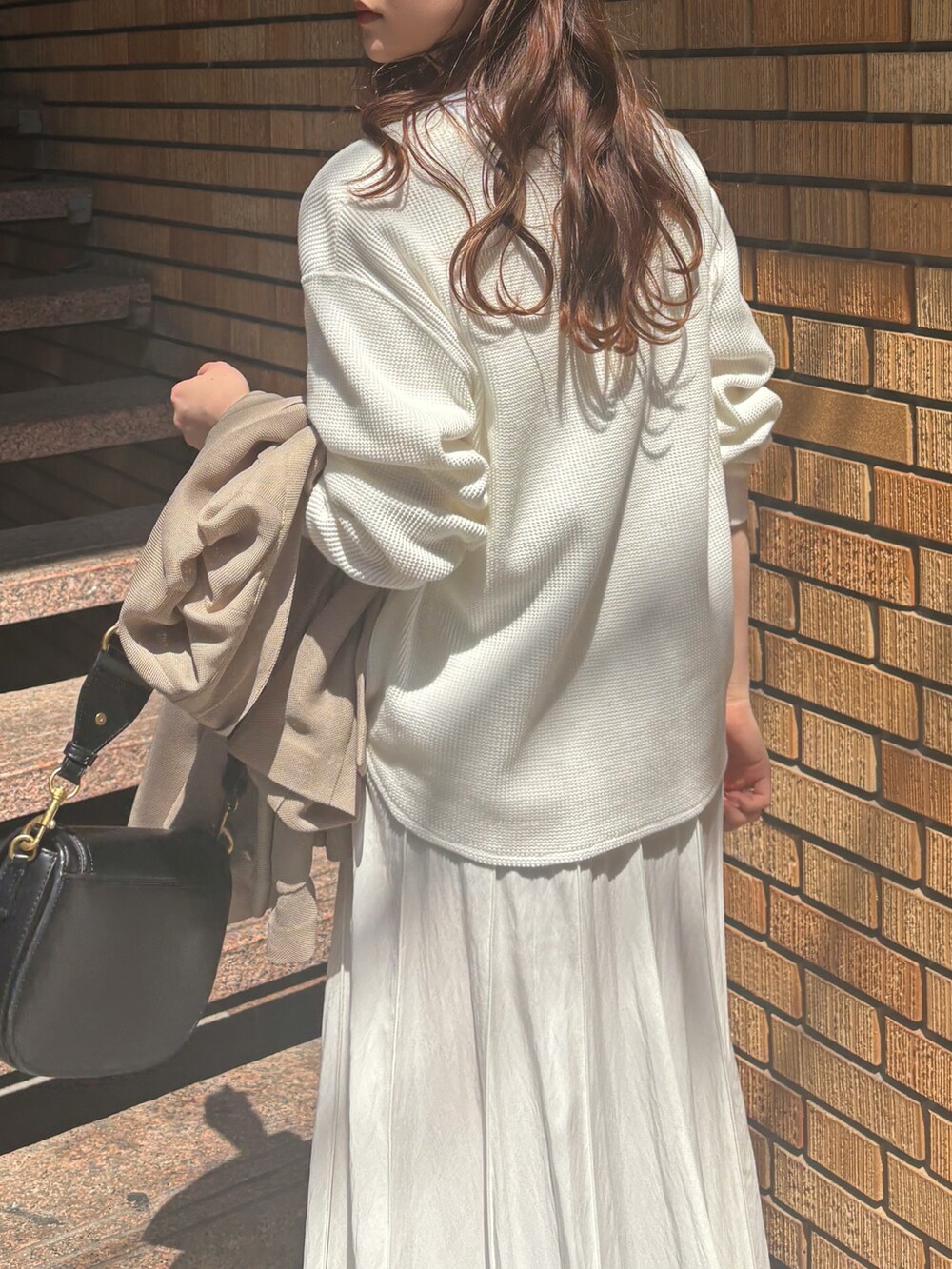 ホワイト系のスカート、ベージュ系のテーラードジャケット、ホワイト系のTシャツ/カットソーを着用したレディースの春コーディネートの4枚目の写真