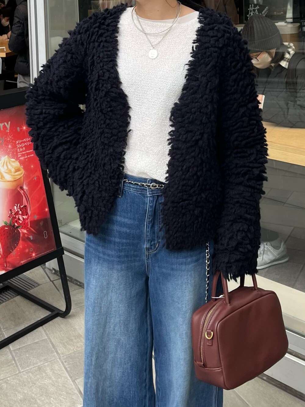 ブルー系のデニムパンツ、ブラウン系のショルダーバッグ、ブルー系のカーディガン/ボレロを着用したレディースの冬コーディネートの5枚目の写真