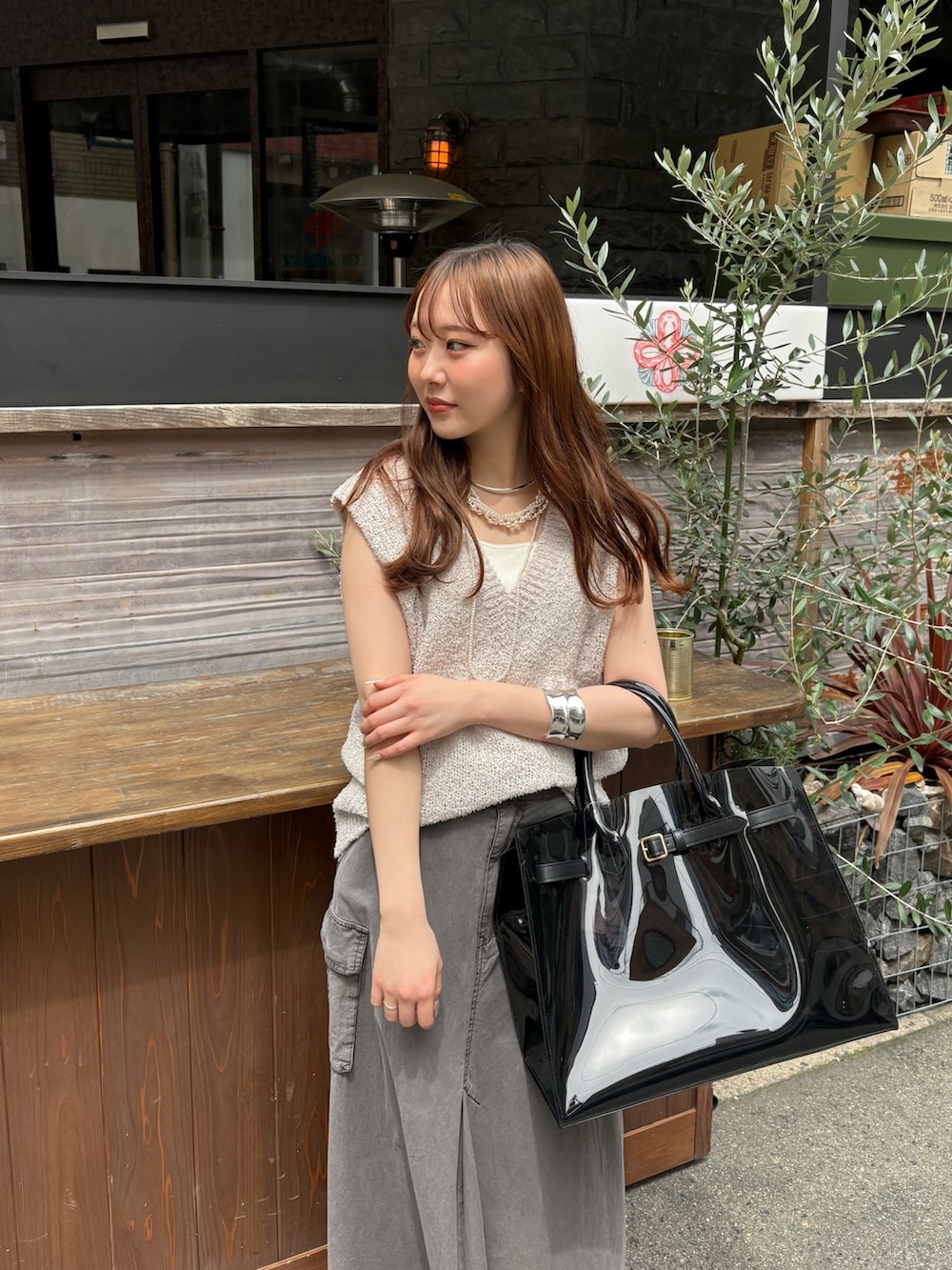 ブラック系のスカート、ブラック系のショルダーバッグ、ベージュ系のニット/セーターを着用したレディースの春コーディネートの3枚目の写真