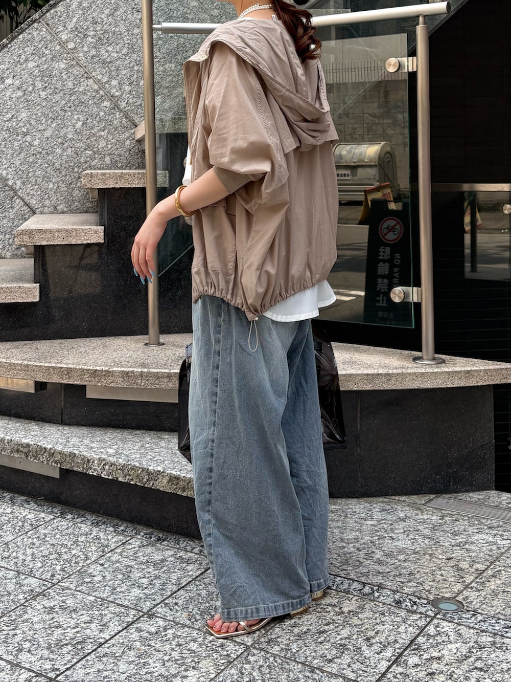 ブルー系のデニムパンツ、ブラック系のショルダーバッグ、ベージュ系のその他アウターを着用したレディースの夏コーディネートの4枚目の写真