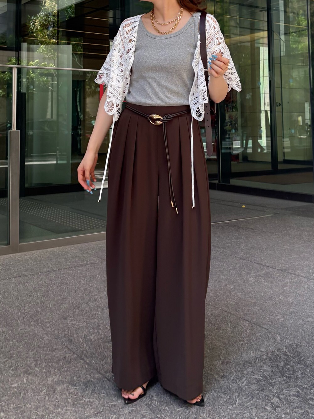 ブラウン系のスラックス、ブラック系のサンダル、グレー系のTシャツ/カットソーを着用したレディースの夏コーディネートの4枚目の写真