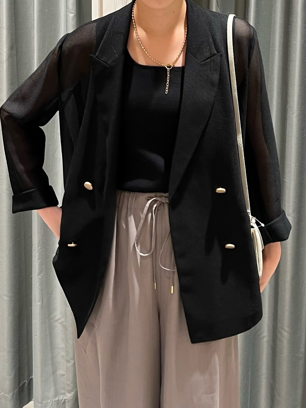 グレー系のその他パンツ、ホワイト系のショルダーバッグ、ブラック系のテーラードジャケットを着用したレディースの夏コーディネートの5枚目の写真