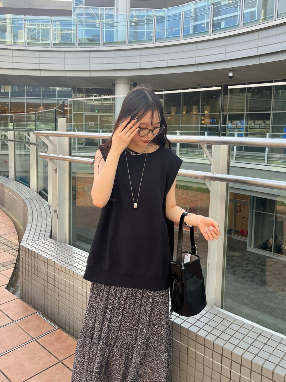 ブラック系のスウェット、ピンク系のスカート、ブラック系のバッグを着用したレディースの夏コーディネートの5枚目の写真