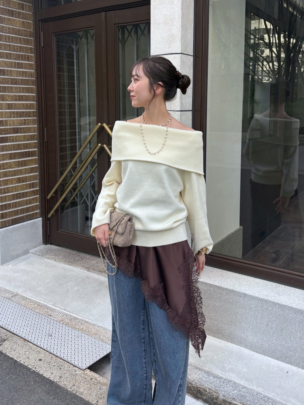 ホワイト系のニット/セーター、ブラウン系のキャミソール、ブルー系のデニムパンツを着用したレディースの冬コーディネートの2枚目の写真