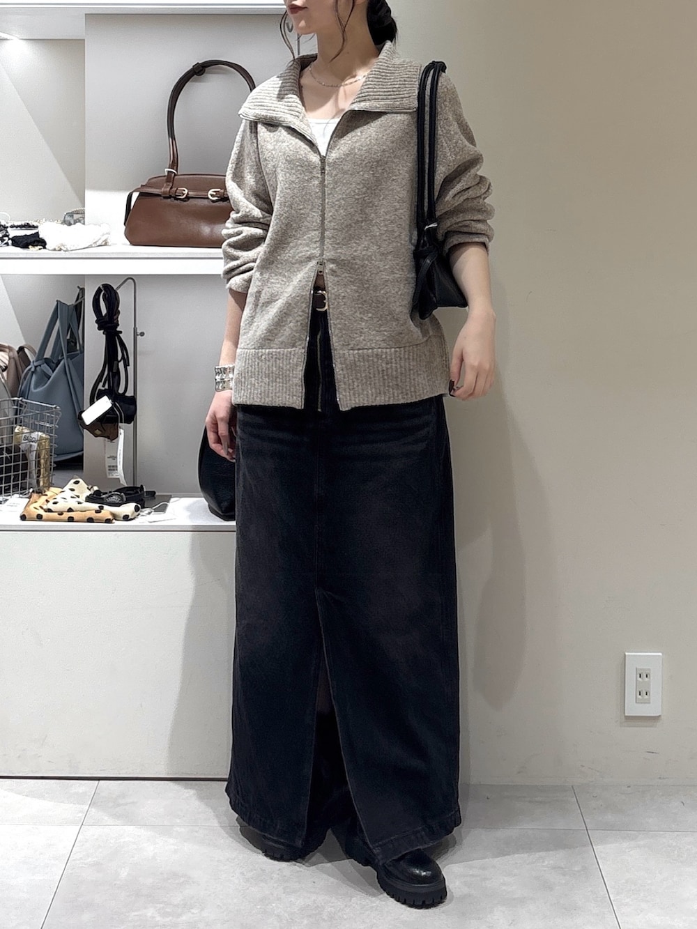 ブラック系のスカート、ベージュ系のカーディガン/ボレロ、ブラック系のトートバッグを着用したレディースの秋コーディネートの2枚目の写真
