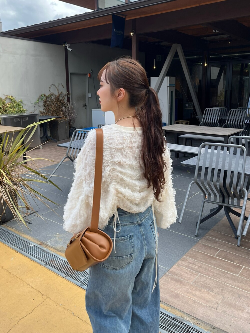 ブルー系のデニムパンツ、ピンク系のバレエシューズ、ブラウン系のショルダーバッグを着用したレディースの秋コーディネートの5枚目の写真