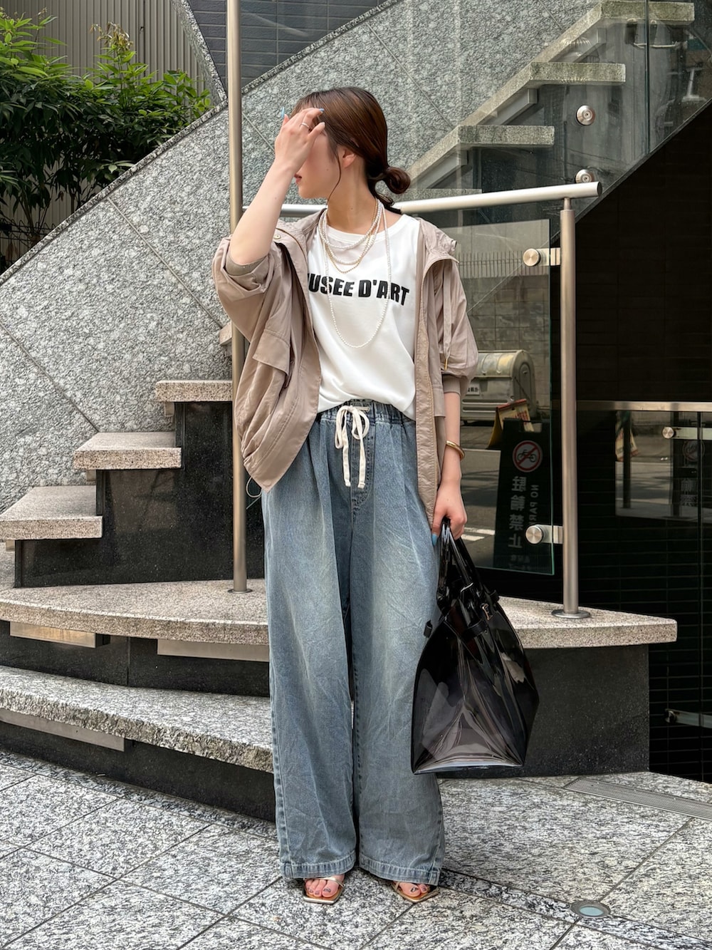 ブルー系のデニムパンツ、ブラック系のショルダーバッグ、ベージュ系のその他アウターを着用したレディースの夏コーディネートの5枚目の写真