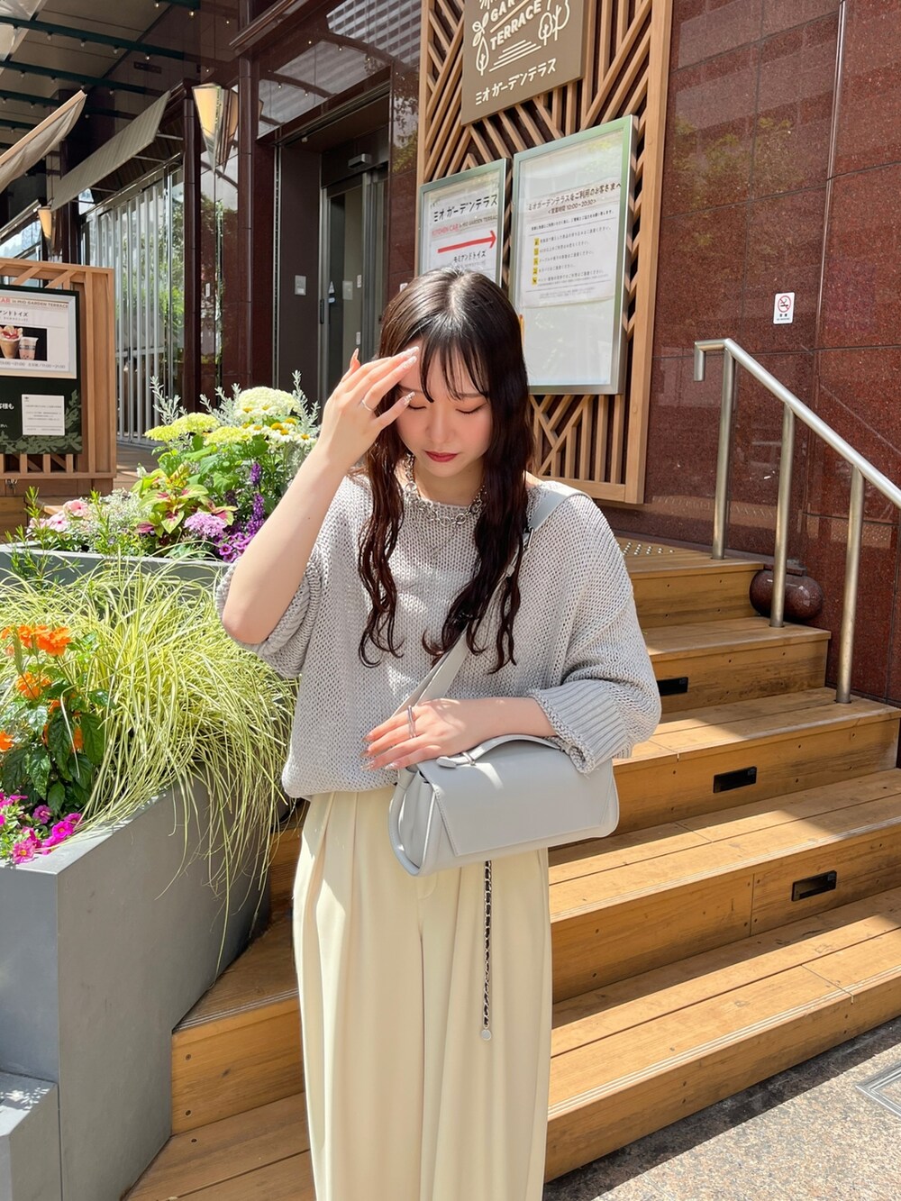 グレー系のニット/セーター、イエロー系のスラックス、グレー系のショルダーバッグを着用したレディースの夏コーディネートの4枚目の写真