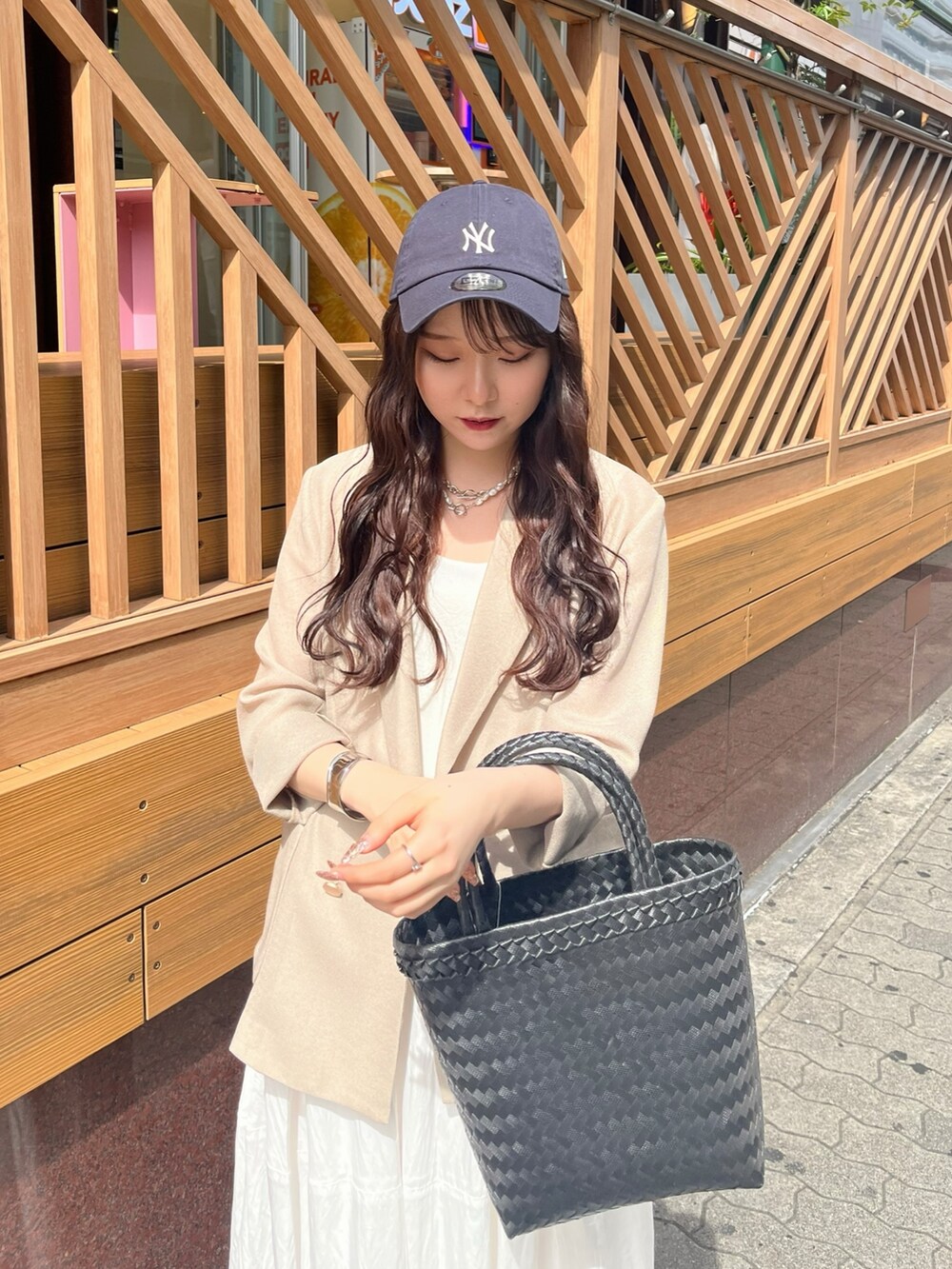 ベージュ系のテーラードジャケット、ホワイト系のワンピース、ブラック系のかごバッグを着用したレディースの夏コーディネートの3枚目の写真