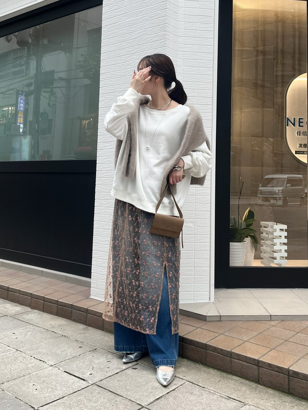 ピンク系のスカート、ブルー系のデニムパンツ、ベージュ系のショルダーバッグを着用したレディースの秋コーディネートの3枚目の写真