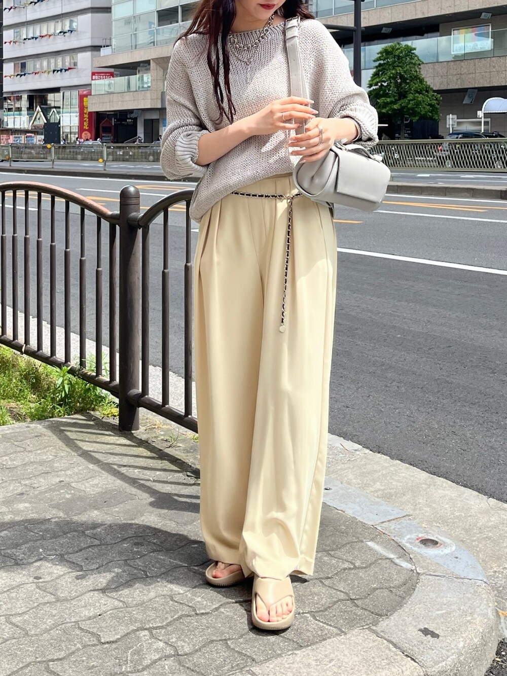 グレー系のニット/セーター、イエロー系のスラックス、グレー系のショルダーバッグを着用したレディースの夏コーディネートの2枚目の写真