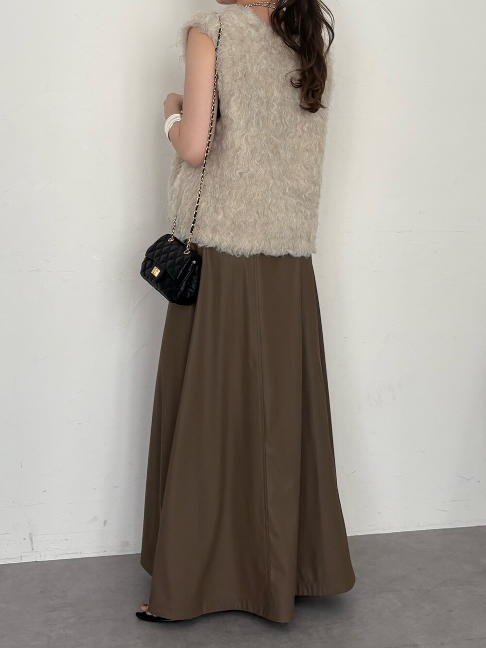 ブラウン系のタンクトップ、ブラック系のショルダーバッグ、ベージュ系のニット/セーターを着用したレディースの夏コーディネートの5枚目の写真