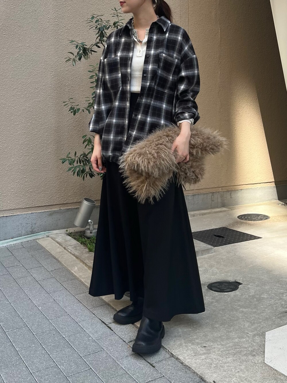 ブラック系のスカート、ベージュ系のショルダーバッグ、ホワイト系のニット/セーターを着用したレディースの秋コーディネートの2枚目の写真