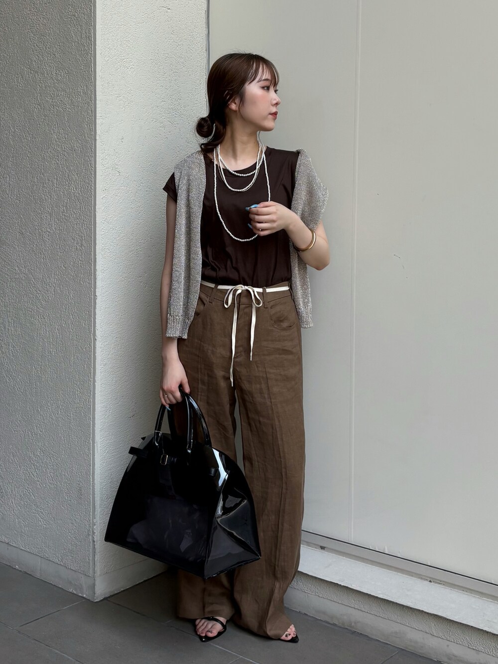 ブラック系のサンダル、ブラック系のショルダーバッグ、ゴールド系のニット/セーターを着用したレディースの夏コーディネートの3枚目の写真