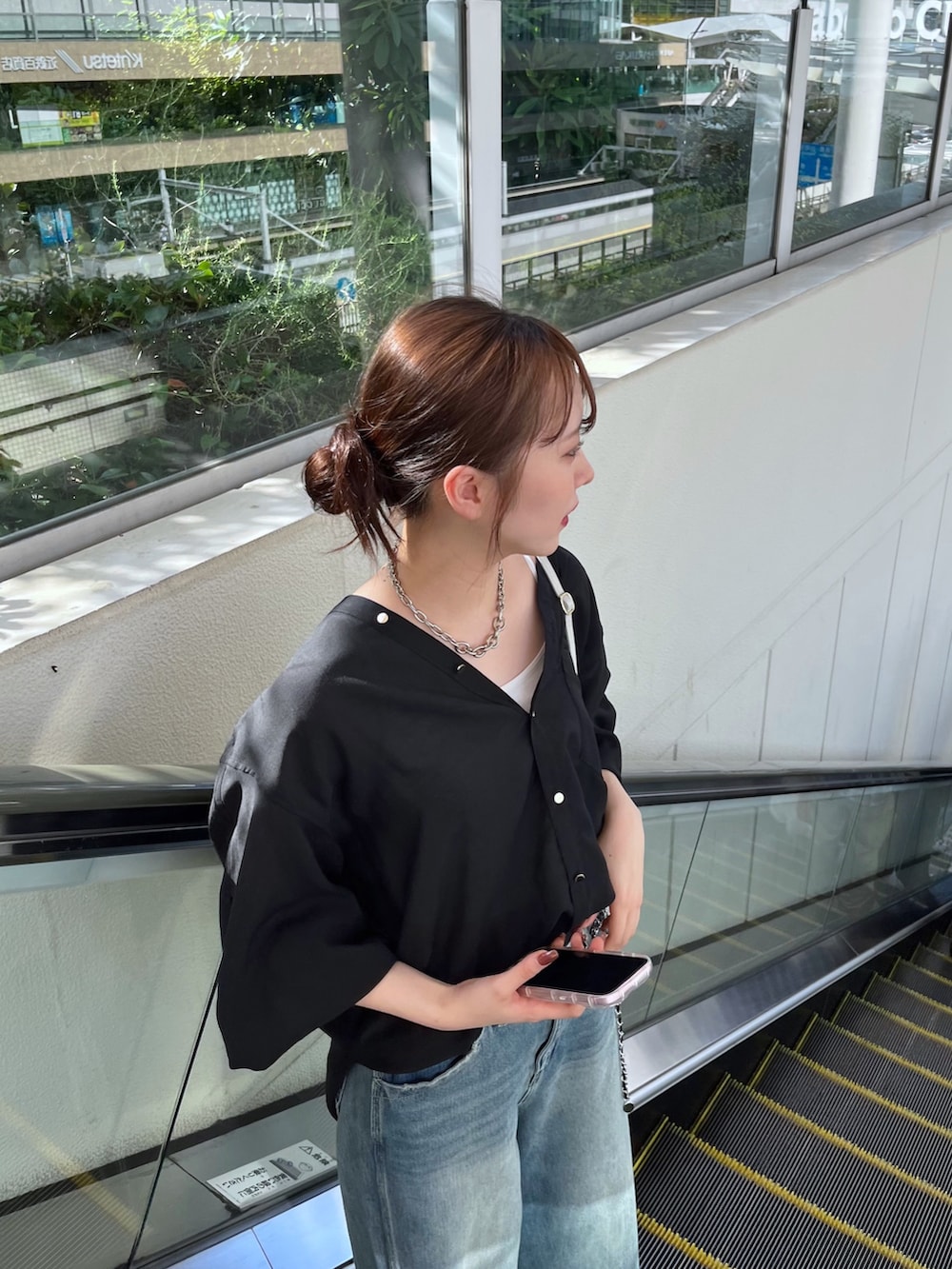 ブルー系のデニムパンツ、ブラック系のシャツ/ブラウス、ホワイト系のショルダーバッグを着用したレディースの夏コーディネートの2枚目の写真