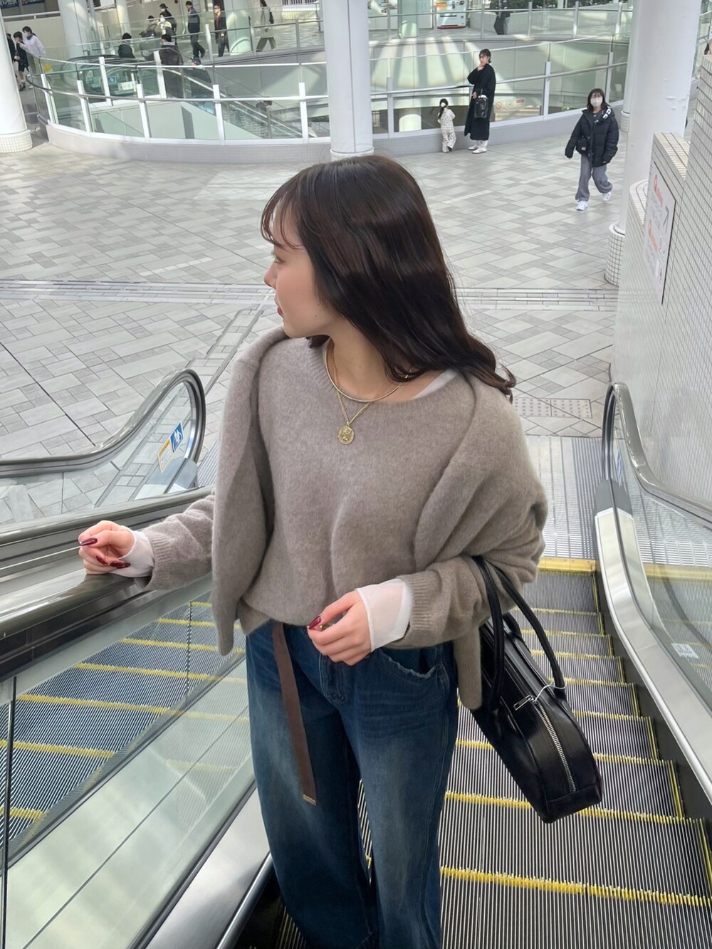 ブルー系のデニムパンツ、ブラウン系のニット/セーター、ブラウン系のカーディガン/ボレロを着用したレディースの冬コーディネートの2枚目の写真