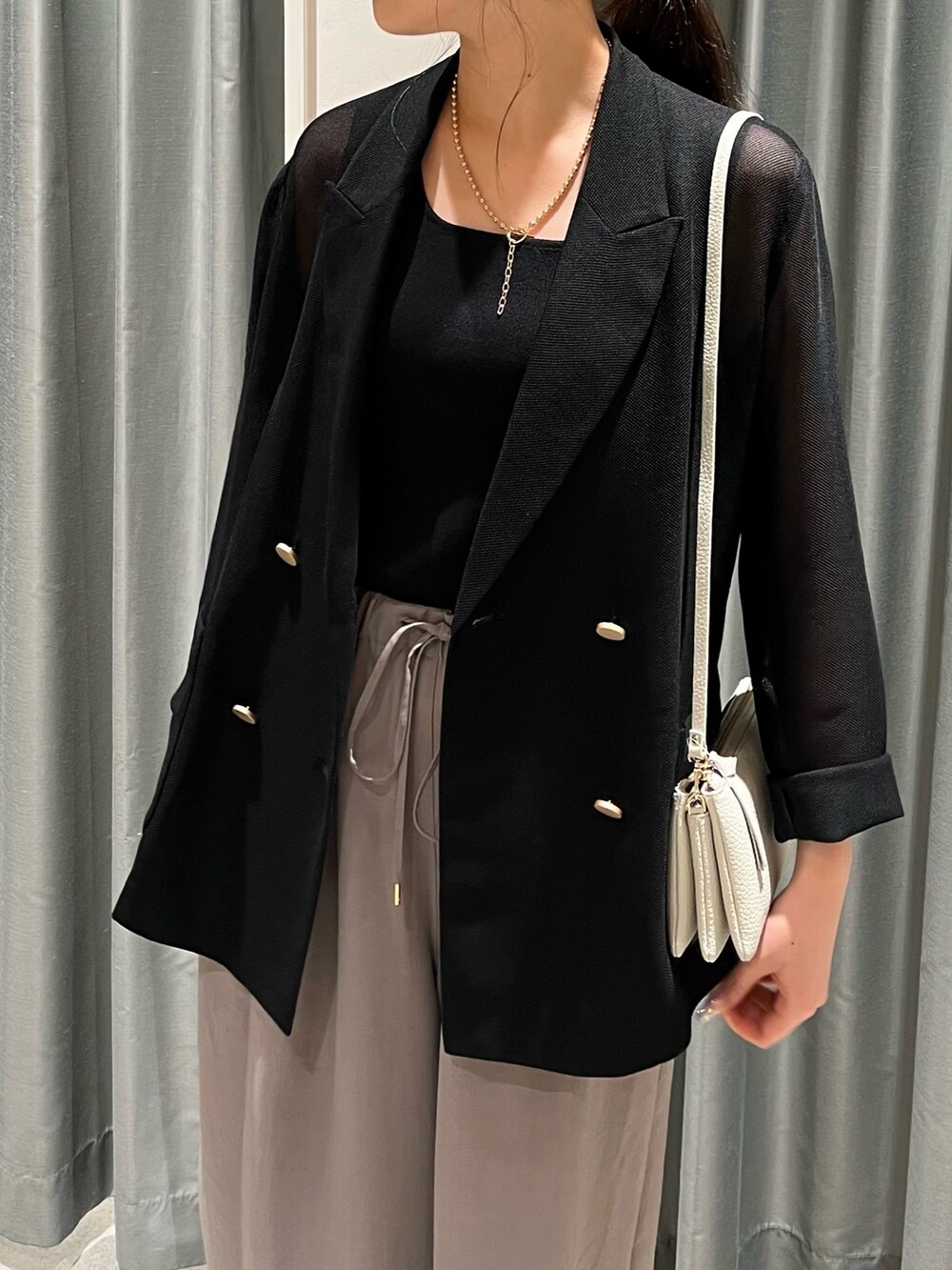 グレー系のその他パンツ、ホワイト系のショルダーバッグ、ブラック系のテーラードジャケットを着用したレディースの夏コーディネートの6枚目の写真