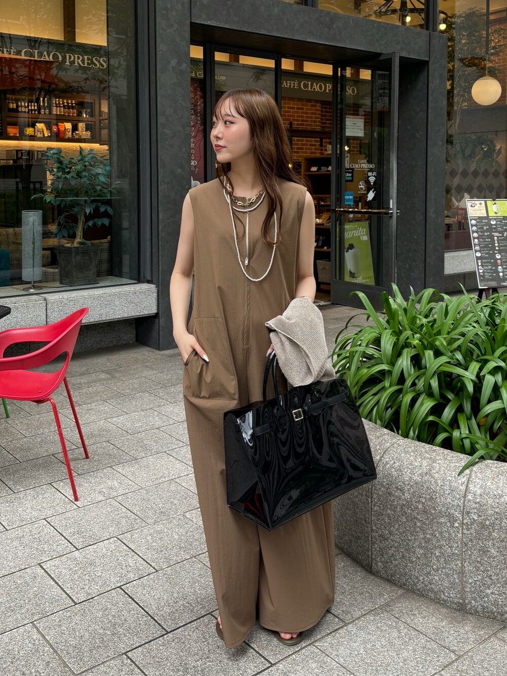 ベージュ系のつなぎ/オールインワン、ブラック系のショルダーバッグ、ゴールド系のニット/セーターを着用したレディースの夏コーディネートの3枚目の写真