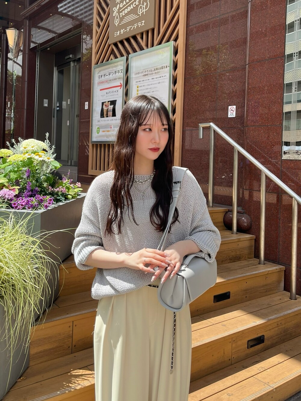 グレー系のニット/セーター、イエロー系のスラックス、グレー系のショルダーバッグを着用したレディースの夏コーディネートの3枚目の写真