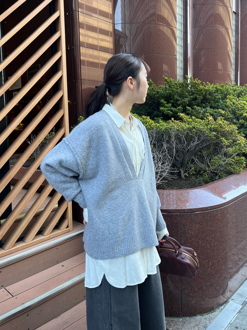 ブラック系のデニムパンツ、ブラウン系のショルダーバッグ、グレー系のその他アウターを着用したレディースの冬コーディネートの4枚目の写真