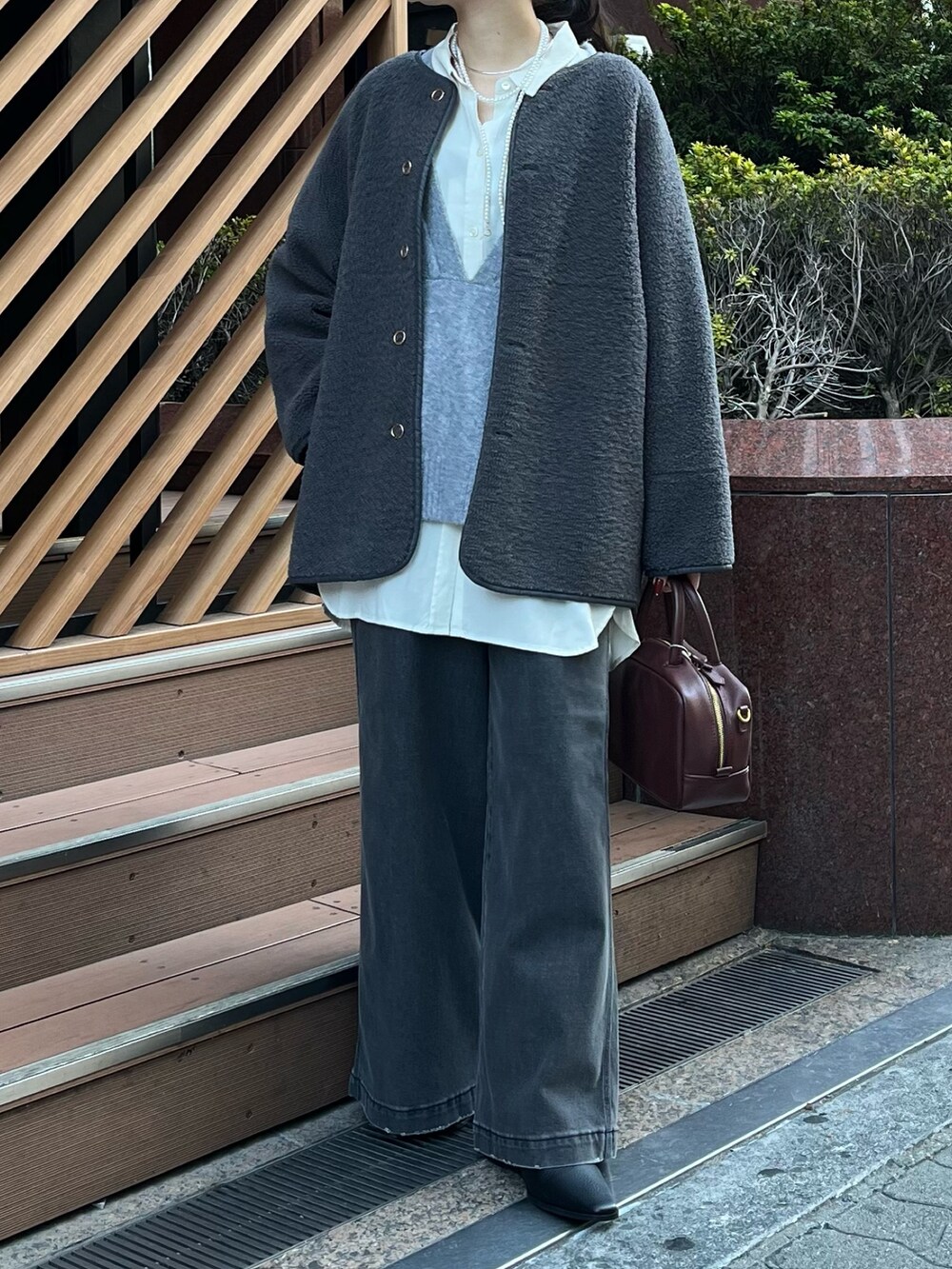 ブラック系のデニムパンツ、ブラウン系のショルダーバッグ、グレー系のその他アウターを着用したレディースの冬コーディネートの2枚目の写真