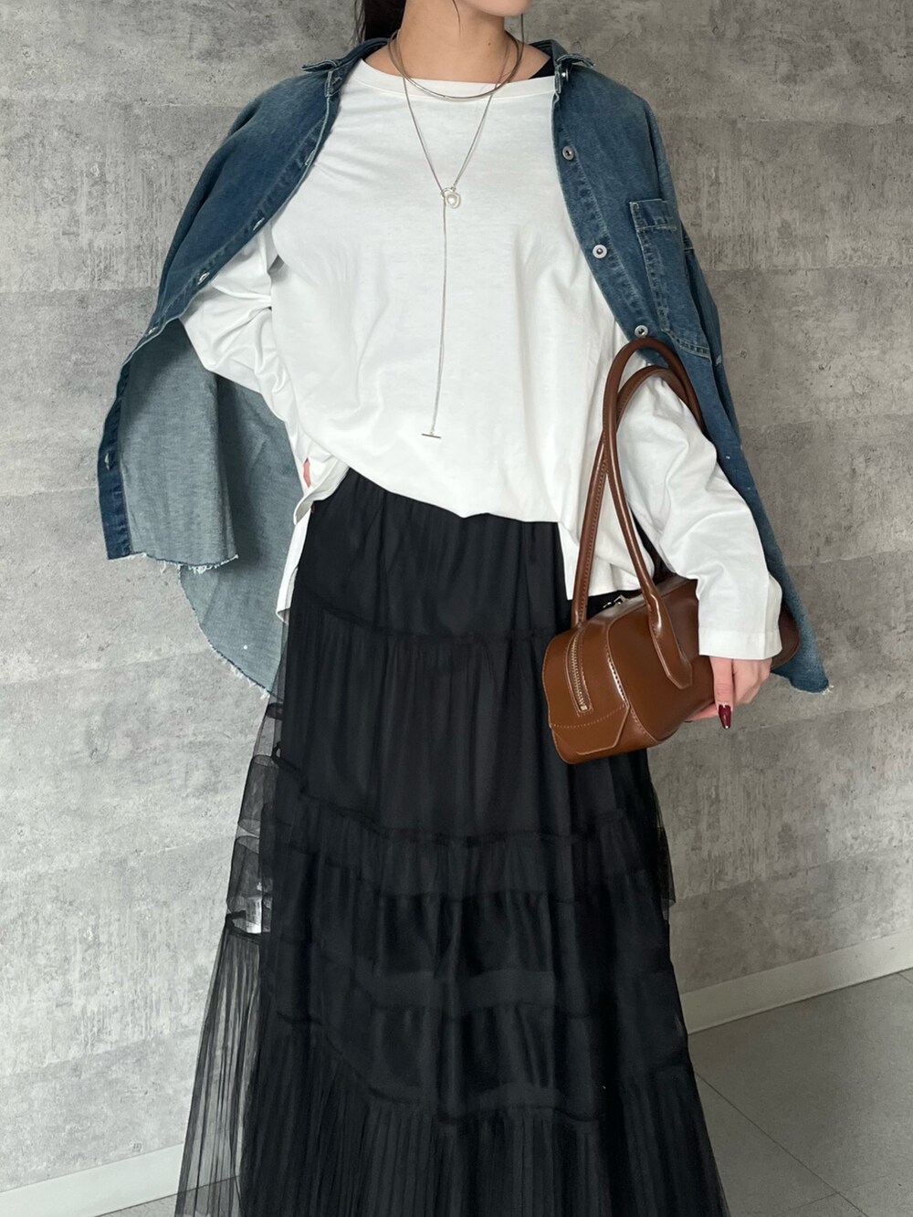 ブラック系のスカート、ブラウン系のショルダーバッグ、ホワイト系のTシャツ/カットソーを着用したレディースの冬コーディネートの4枚目の写真