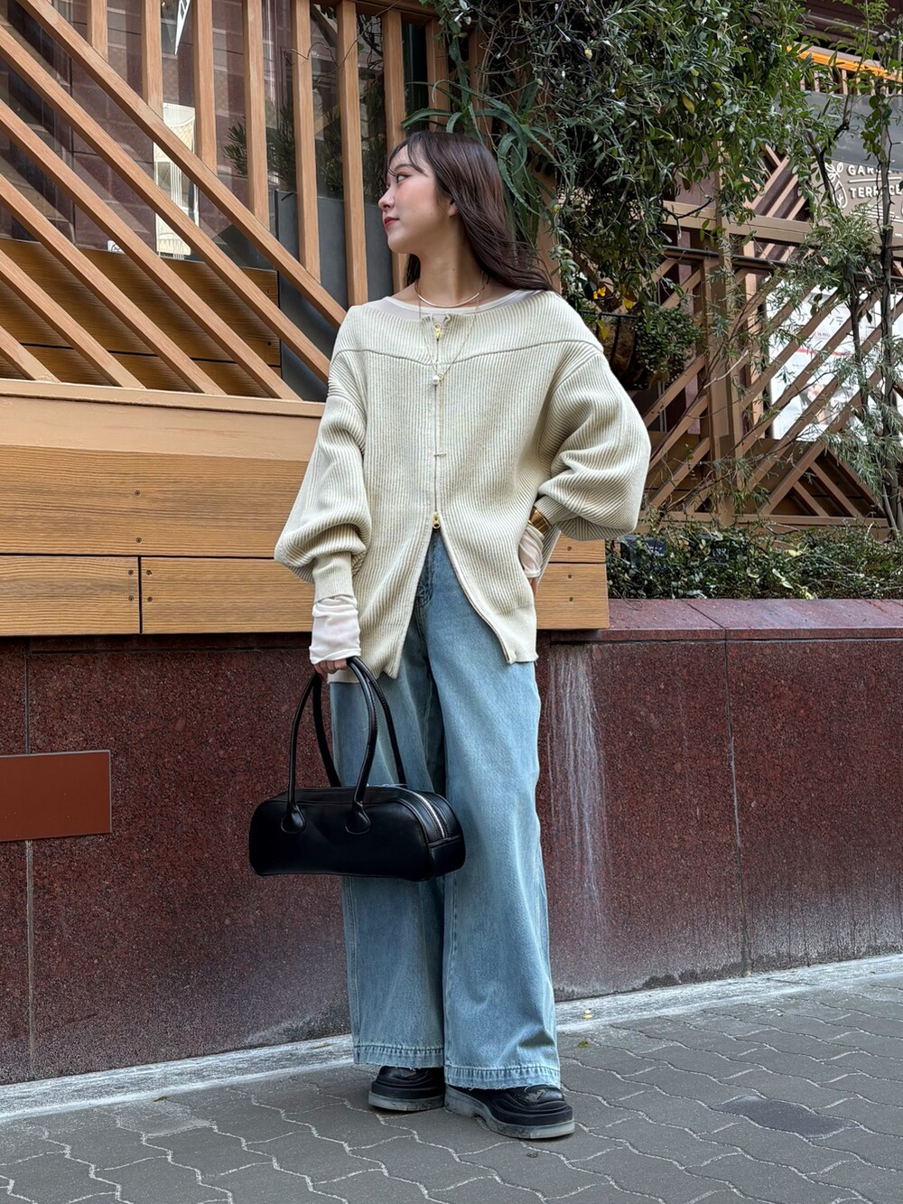 ブルー系のデニムパンツ、ブラック系のショルダーバッグ、ベージュ系のニット/セーターを着用したレディースの冬コーディネートの4枚目の写真