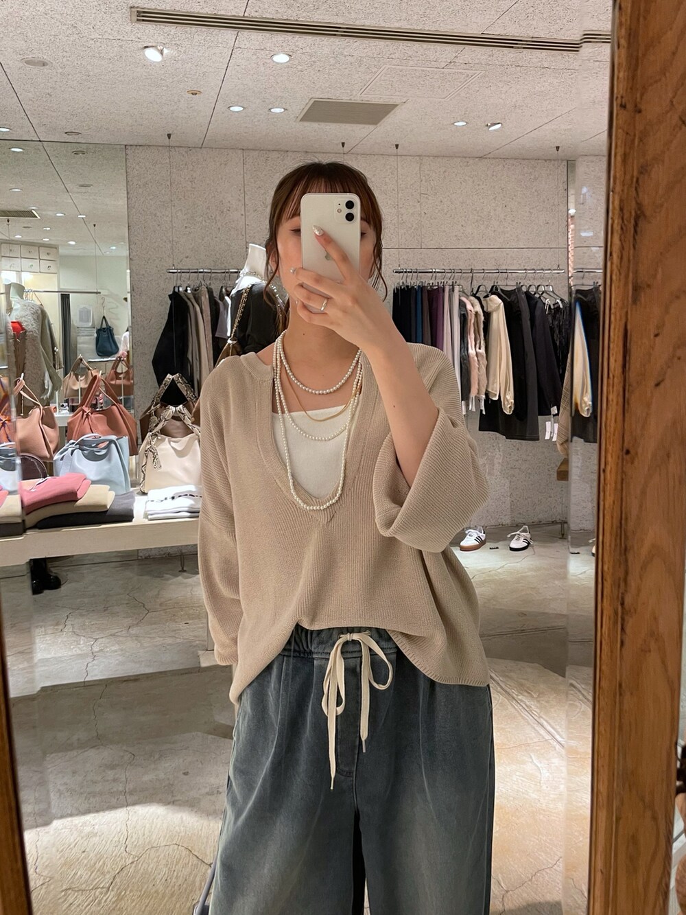 ブルー系のショルダーバッグ、ブルー系のその他パンツ、ベージュ系のニット/セーターを着用したレディースの秋コーディネートの2枚目の写真