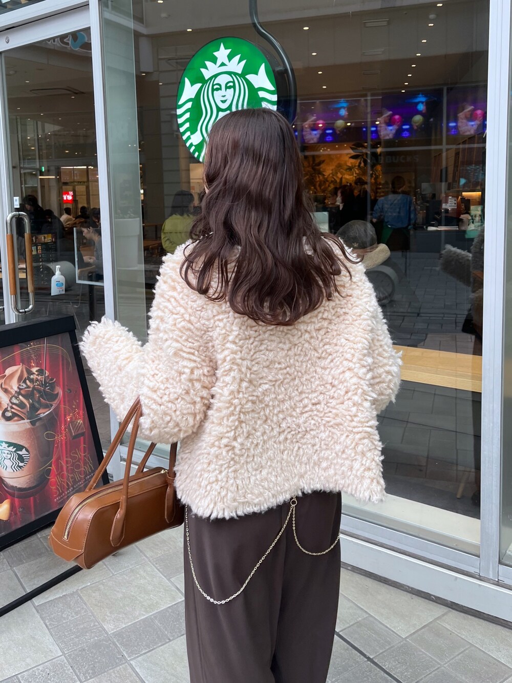 ブラウン系のスラックス、ブラウン系のショルダーバッグ、ベージュ系のカーディガン/ボレロを着用したレディースの冬コーディネートの4枚目の写真