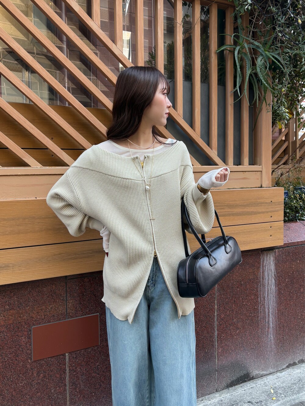 ブルー系のデニムパンツ、ブラック系のショルダーバッグ、ベージュ系のニット/セーターを着用したレディースの冬コーディネートの5枚目の写真