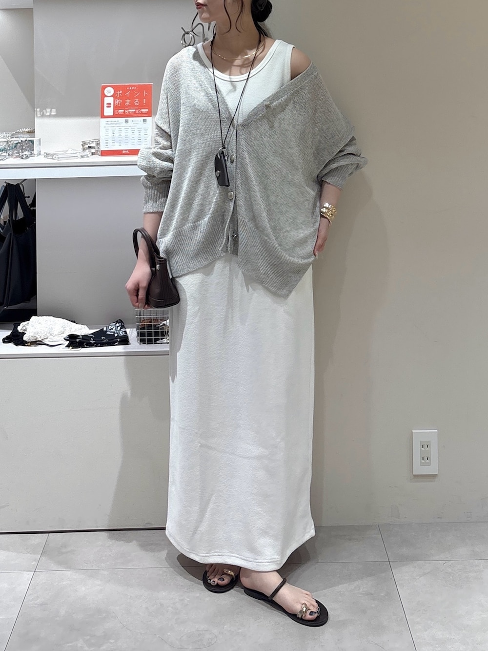 ホワイト系のワンピース、グレー系のカーディガン/ボレロ、ブラウン系のショルダーバッグを着用したレディースの夏コーディネートの2枚目の写真