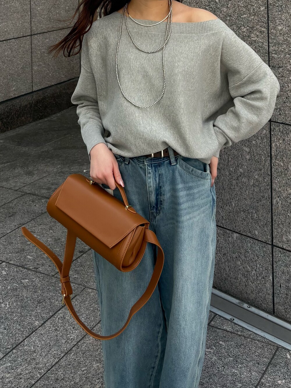 ブルー系のデニムパンツ、グレー系のニット/セーター、ブラウン系のショルダーバッグを着用したレディースの春コーディネートの2枚目の写真