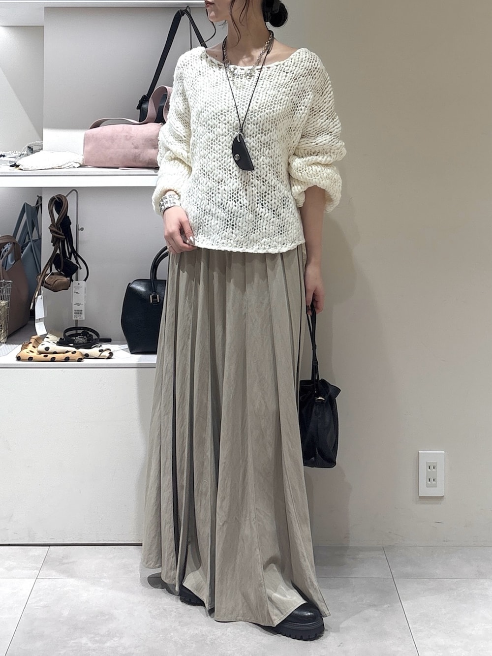 ブラック系のトートバッグ、ベージュ系のスカート、ホワイト系のニット/セーターを着用したレディースの秋コーディネートの2枚目の写真