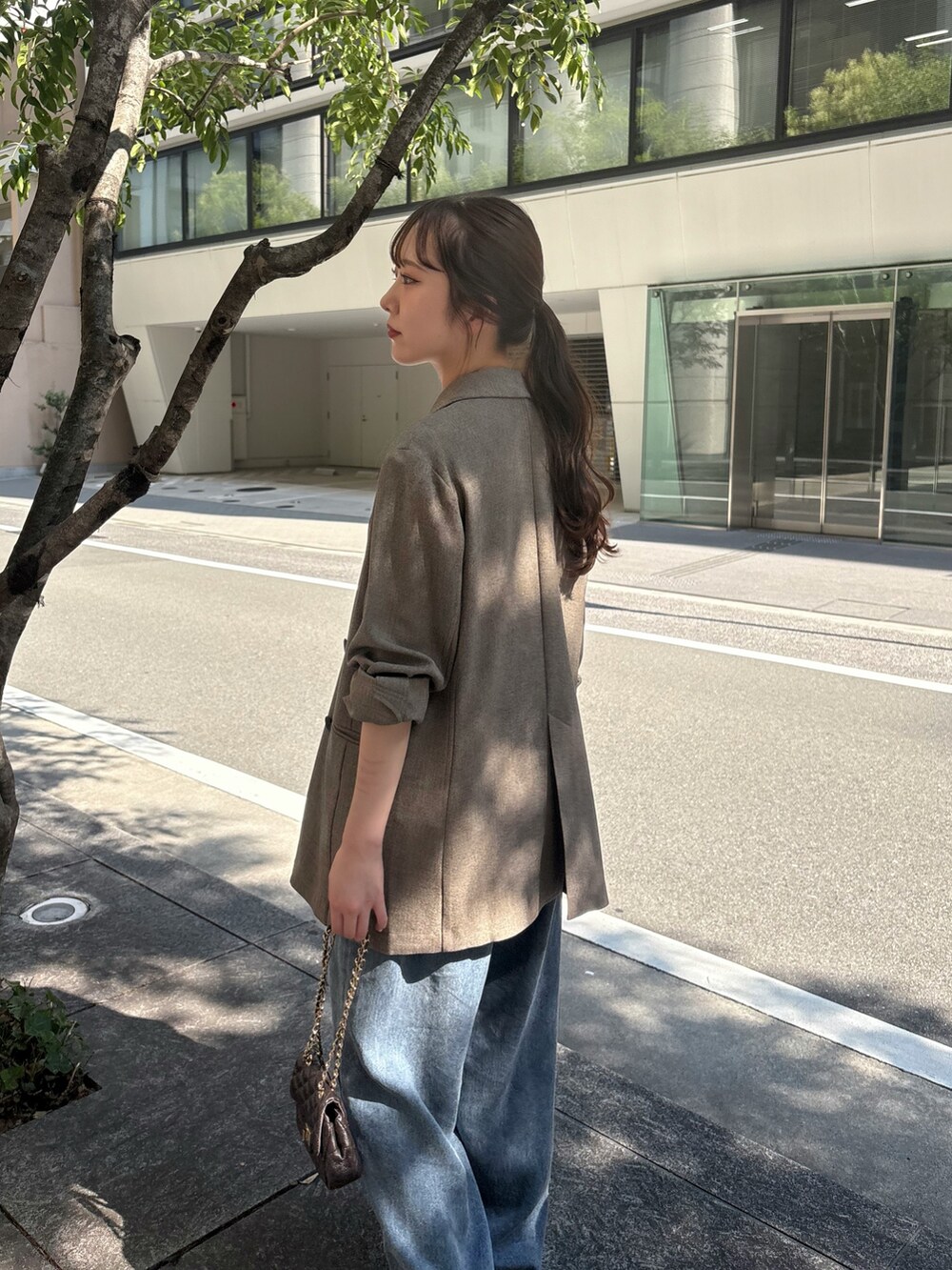 ブラウン系のテーラードジャケット、グリーン系のシャツ/ブラウス、ブルー系のデニムパンツを着用したレディースの夏コーディネートの4枚目の写真