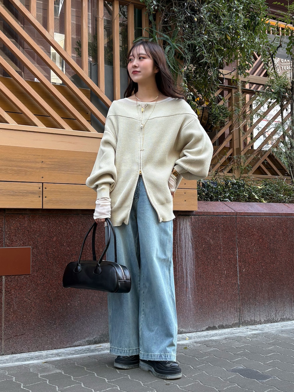 ブルー系のデニムパンツ、ブラック系のショルダーバッグ、ベージュ系のニット/セーターを着用したレディースの冬コーディネートの3枚目の写真