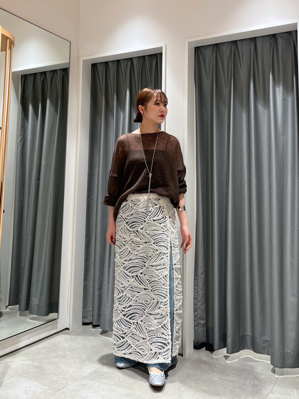 ブルー系のデニムパンツ、シルバー系のバレエシューズ、ホワイト系のスカートを着用したレディースの夏コーディネートの4枚目の写真